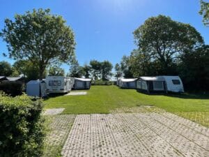 Campingplaatsen met caravans en luifels op een grasterrain op een zonnige dag - klantreis campingwebsite